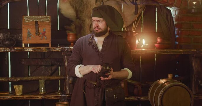Merchant checks roots in capsule in store. Serious bartender in medieval dress takes potion ingredients out of decorative container in tavern. Seller goods