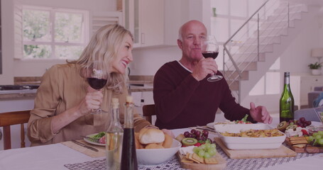 Image of confetti over diverse group of seniors drinking wine