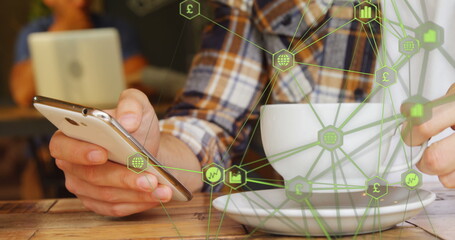 Globe of digital icons against mid section of man using smartphone and drinking coffee at a cafe