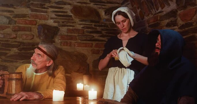 Men feared of new guest and maid cleans glass in tavern. Constant visitors look with fright at newbie while bored waitress works in pub. Fantasy tale