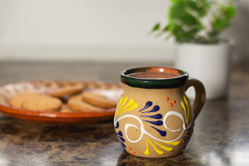 Traditional Mexican cup with hot chocolate drink. champurrado and plate with cookies