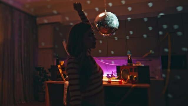 Closed eyes woman dancing in apartment after night party disco ball close up.