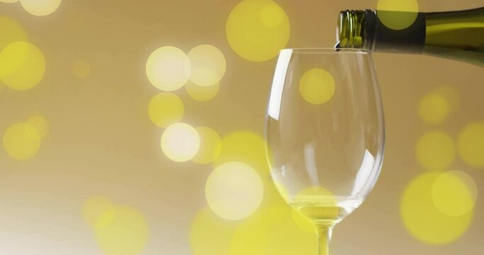 Composite of white wine being poured into glass over yellow spots