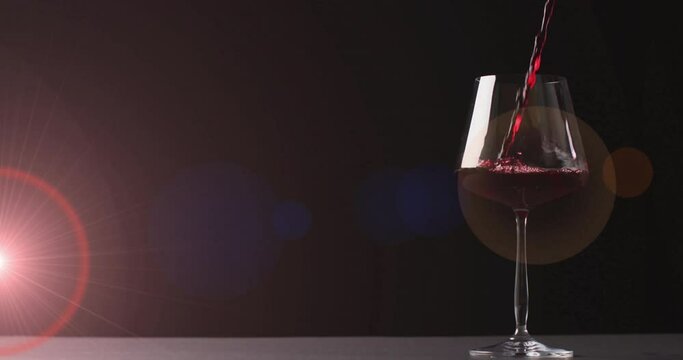 Composite of red wine being poured into glass over dark red background