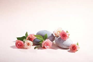 A stone and pink rose against light yellow background. An empty space for display cosmetic products, food and props.