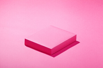 a pink square podium against dark pink background. An empty platform for display cosmetic products,...