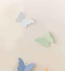 Fototapeta na wymiar A pastel-toned light beige backdrop of a paper butterfly model, a view of the top, a paper white and green and blue butterfly. An empty platform for display cosmetic products, food and props
