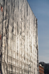 Scaffolding plastic sheeting cover on big building. Fully covered