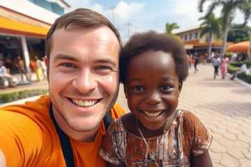 Caucasian man volunteering in african village takes selfie with children - community support concept
