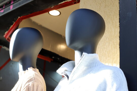 A mannequin stands in a display case behind glass in a large supermarket.