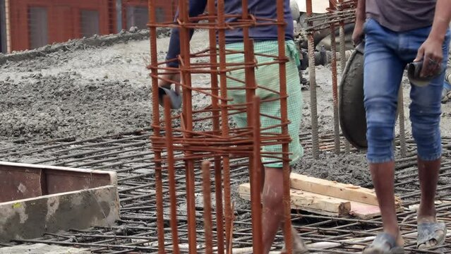 Manual workers working on concrete construction site close up.