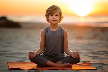 Fototapeta na wymiar Young boy practicing yoga on the beach at sunset. Healthy lifestyle concept