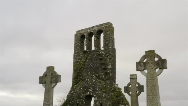 Engraved stone cross headstones with ornate designs covered in moss and lichens