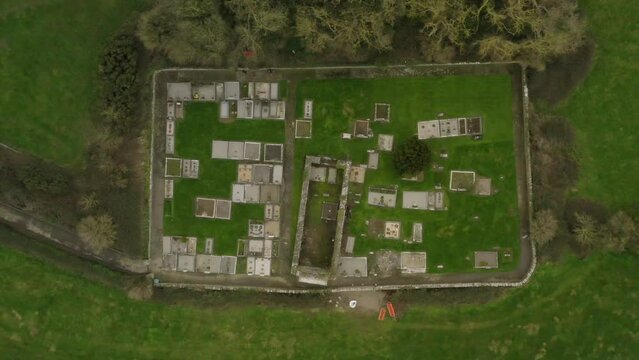 Bird's eye view above graveyard concrete plots and walls in lush green Irish countryside