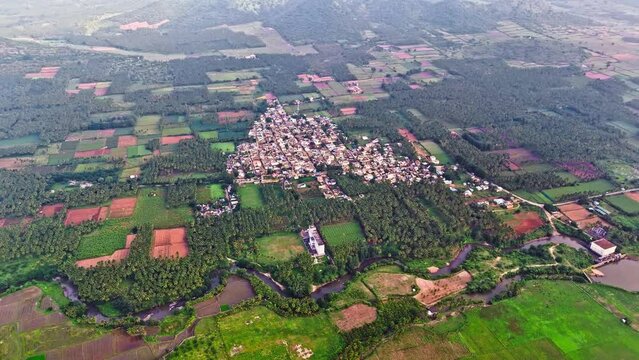 Profile view of an isolated city surrounded by greenery and hills at background during daytime in Theni, Tamil Nadu. Drone shot.
