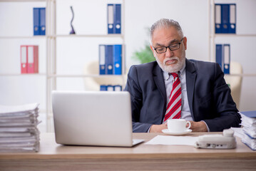 Old male employee drinking coffee during break