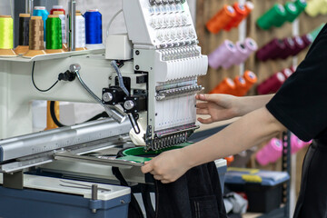 a female worker using and  preparing automatic tailoring machine for work  on clothing manufature...