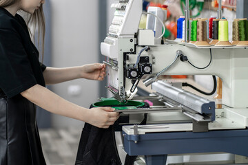 a female worker using and  preparing automatic tailoring machine for work  on clothing manufature...