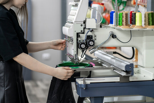 a female worker using and  preparing automatic tailoring machine for work  on clothing manufature factory