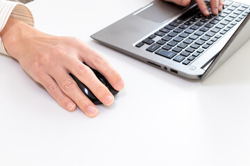 パソコンとマウスを使って作業する人物