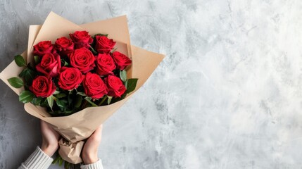 Hands holding a bouquet of vibrant red roses wrapped in brown paper