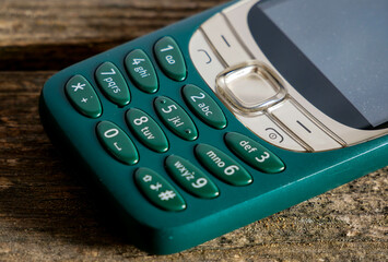 Old, vibrant green mobile phone on aged weathered pine wood boards.