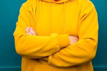 Fotobehang Portrait of cheerful adult handsome man smile with yellow sweater clothes and blue wall in backgorund - happy people and copy space - beard 50 years old male with black eye glasses © simona