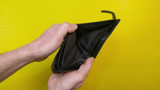Empty black leather wallet. Man's hands open empty billfold, view from top