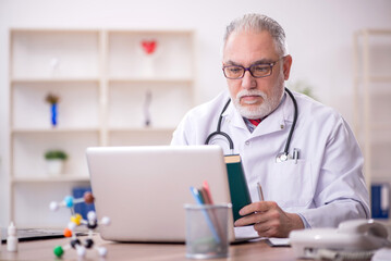 Old male doctor working in the clinic