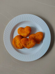 Heart-shaped fried chicken nuggets on a white plate