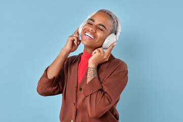 Young cheerful pretty African American woman in casual clothes and headphones experiences euphoria...