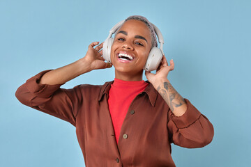 Young laughing enthusiastic African American woman using wireless headphones to listen to...