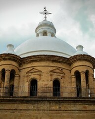 a large tan and white building with an arched roof and a cross