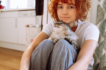 Portrait red-haired curly teenage girl with favorite fluffy domestic cat