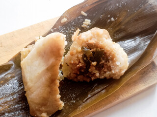 Zongzi or Bakcang. Chinese savoury sticky rice dumplings in bamboo leaves wrapping,One has been cut halved.