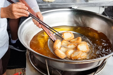 Hawker scooping out cooked Ham Chim Peng from wok, a popular Chinese street food in Malaysia