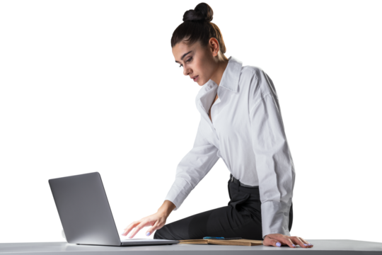 Engrossed businesswoman working on laptop, kneeling on desk for better focus