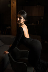 Obraz na płótnie Canvas Elegant woman in a black dress posing in an apartment. Fashion shooting concept