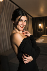 Fototapeta premium Elegant woman in a black dress posing in an apartment. Fashion shooting concept