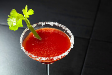 Bloody Mary cocktail with celery on a black background.