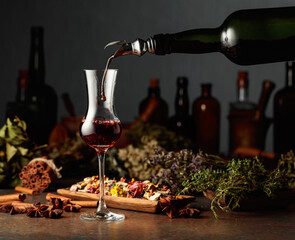 Brown herbal liquor or balm is poured from a vintage bottle into a glass.