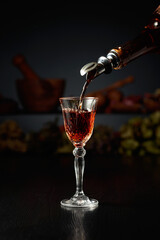 Brown herbal liquor or rum is poured from a vintage bottle.