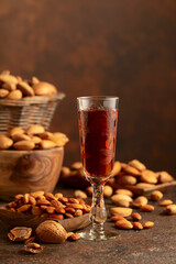 Italian liqueur Amaretto with almonds nuts on a brown background.