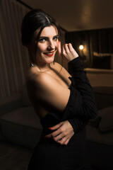 Naklejka premium Elegant woman in a black dress posing in an apartment. Fashion shooting concept