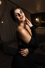 Elegant woman in a black dress posing in an apartment. Fashion shooting concept