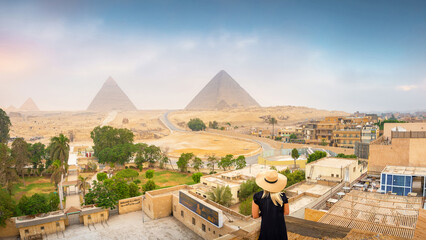Giza, Egypt - A blonde haired woman looks at the pyramids during sunrise in Giza, Egypt