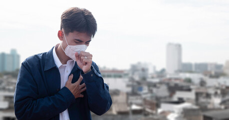 PM 2.5 respiratory protection mask prevents air pollution and dust beyond safety limits. A sick young man wears a mask to protect against PM 2.5. Haze, dust and smog with bad weather.