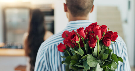 Happy couple, red roses and kiss for surprise, anniversary or valentines day in kitchen at home. Face of young man and woman smile with flowers for romantic gift, love or care in celebration at house