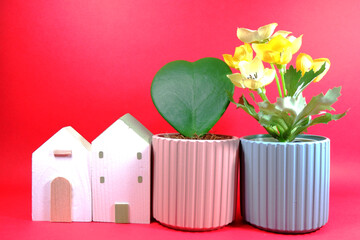 Valentine's day concept: heart shaped cactus in pink ceramic plant pot and wooden crafted little houses building mock up for interior decoration on red background horizontal copy space stock photo