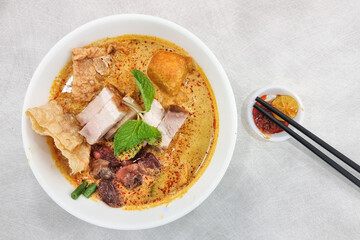 Delicious curry mee or curry laksa with roast pork and fresh raw cockerel